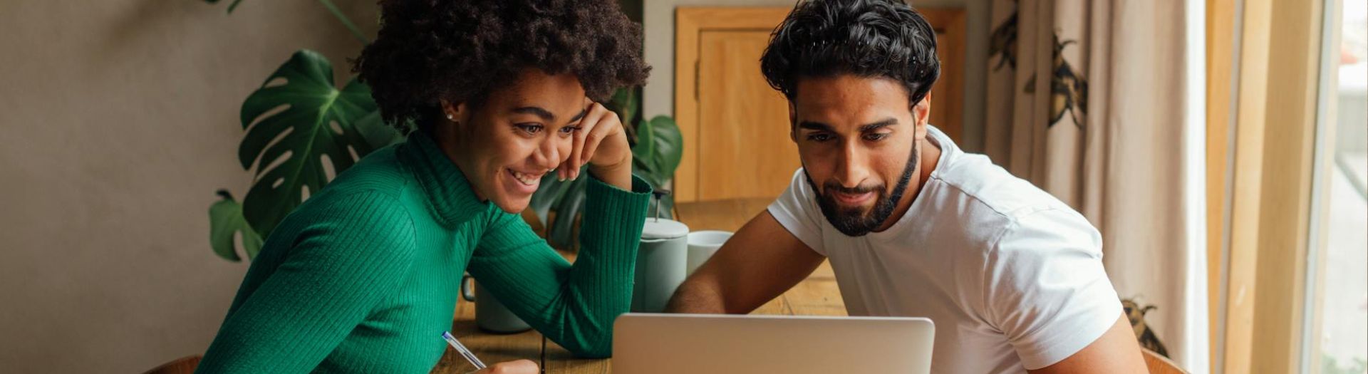 Two people looking at a laptop together in a home setting.